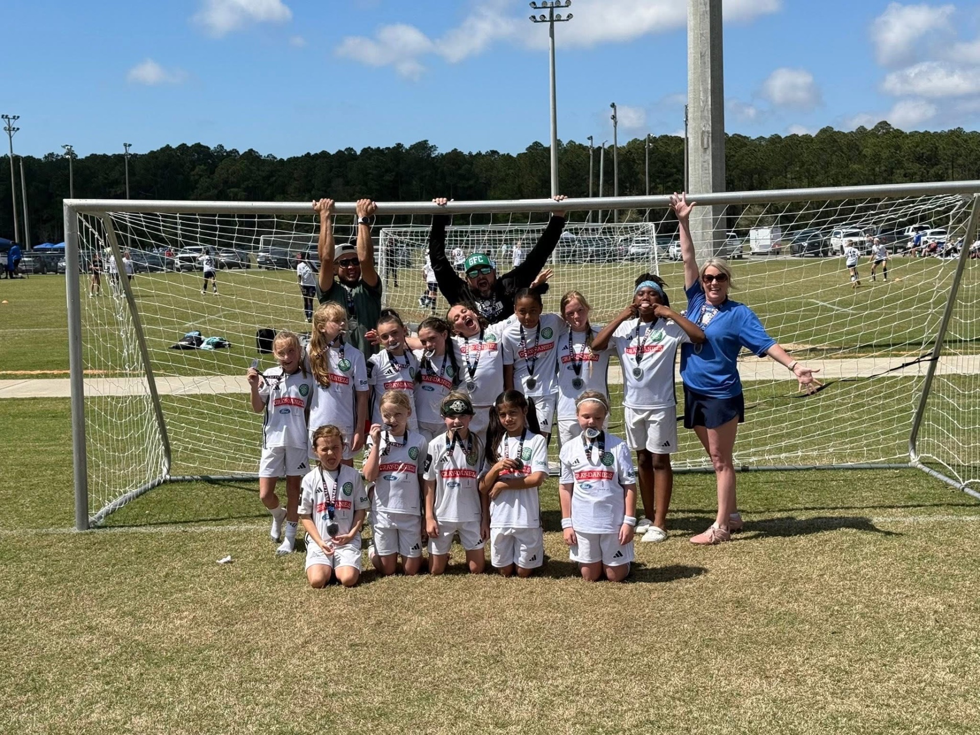 GFC girls team celebrating with medals in the goal